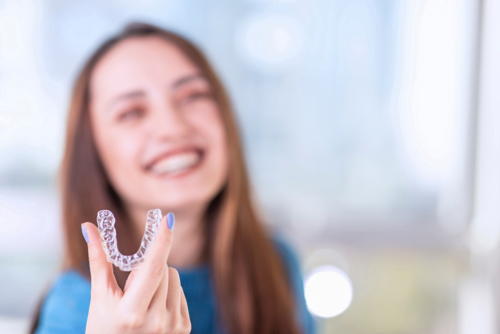 a person smiling and holding a clear plastic retainer